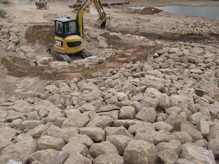 18-Five Point Lake Stabilization, mini-excavator placing riprap in channel