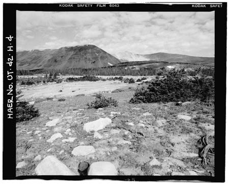 HAER photo of downstream face of Five Point Lake Dam, earth-moving scars from Dam construction in foreground, July 1985